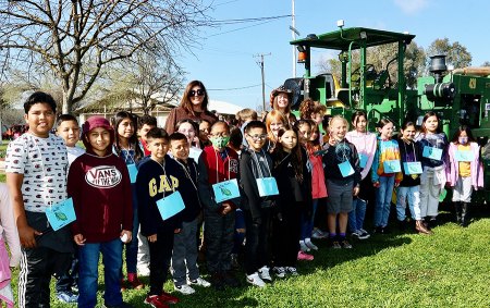 Mrs. Barcellos' third grade class pose in front of a tractor during their time at Farm Day.